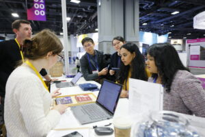 people gathered around a table holding laptops and colorful postcards